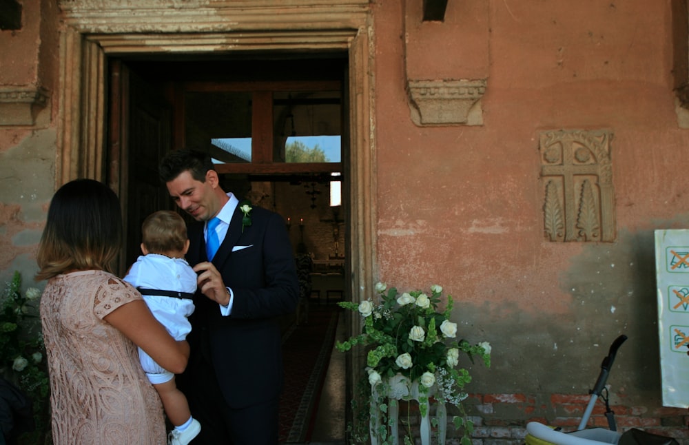 man in black suit standing beside woman in white shirt