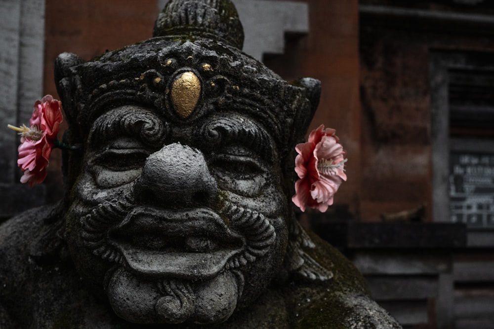 black concrete buddha statue with pink flower on head