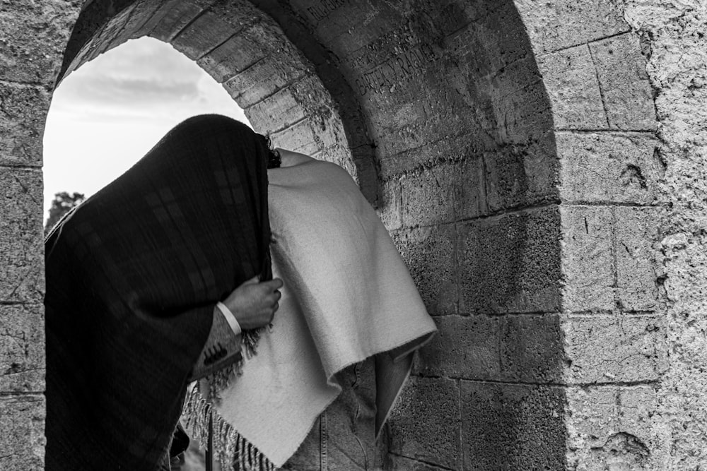 grayscale photo of person covering face with white textile