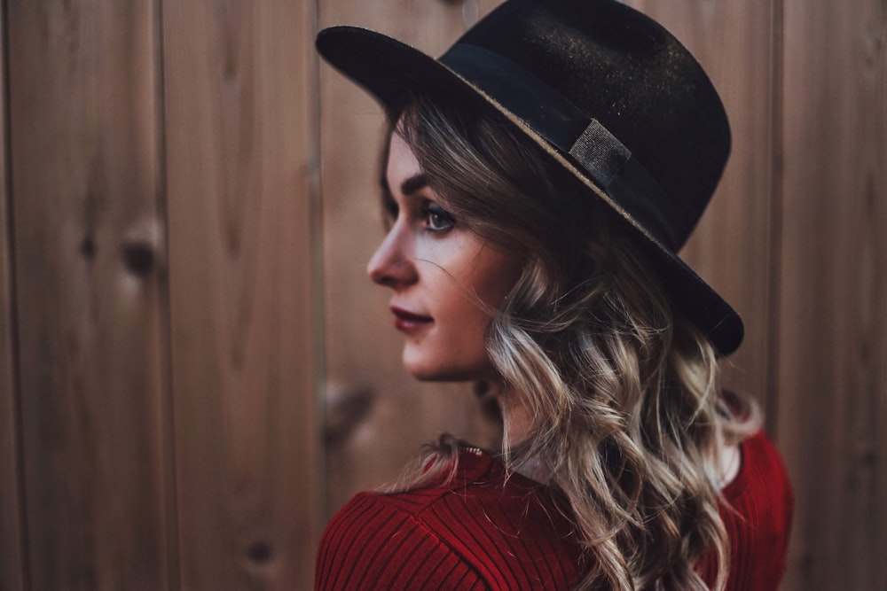 woman in red knit sweater wearing black fedora hat