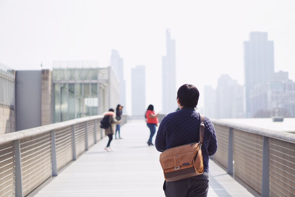 man in black and brown backpack walking on sidewalk during daytime