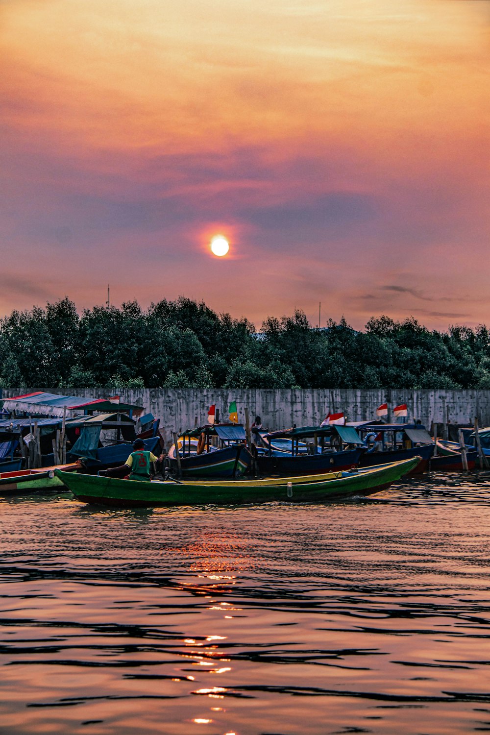 Grünes und blaues Boot auf dem Wasser bei Sonnenuntergang