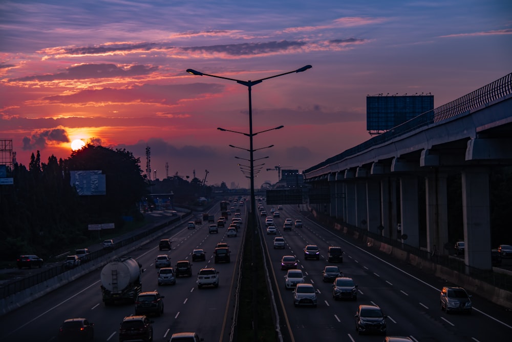 Coches en la carretera durante la puesta de sol