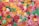 A close-up view of an assortment of colorful gummy candies shaped like small hearts. The candies are coated with a layer of sugar, giving them a slightly frosted appearance. The vibrant colors include red, green, orange, and yellow.