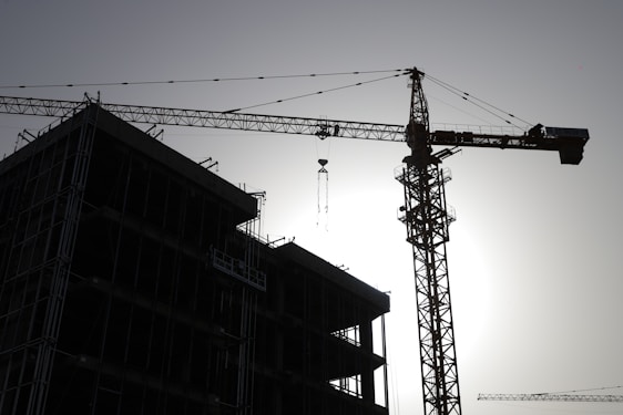 A panoramic view of a large-scale bridge construction site at dawn, showcasing cranes and workers in action.