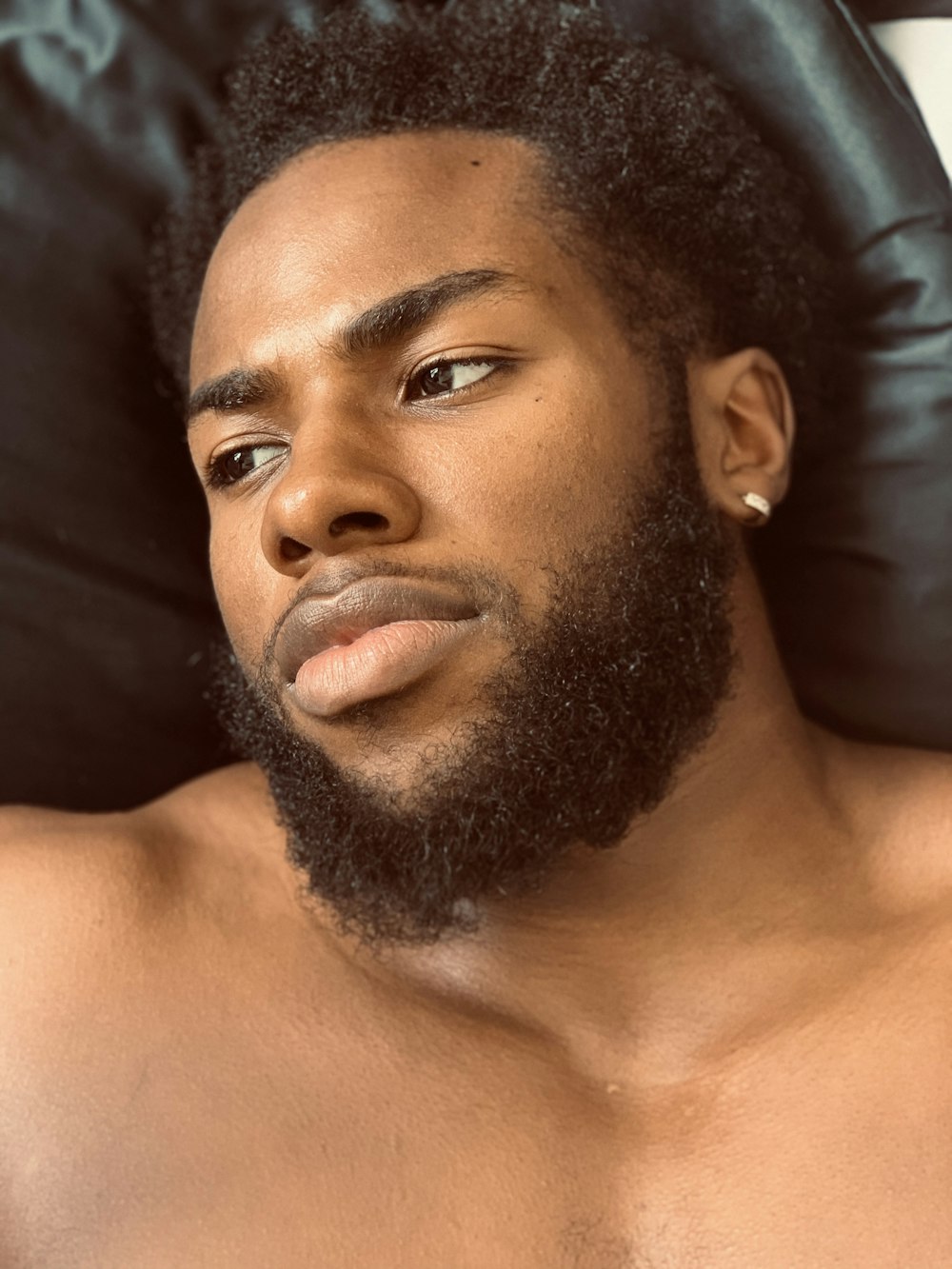 topless man lying on black textile