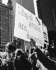 grayscale photo of sign that says stupid people are dangerous