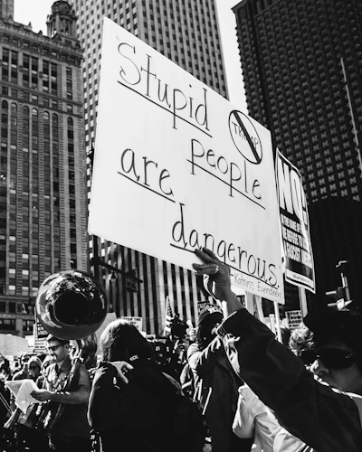 grayscale photo of sign that says stupid people are dangerous