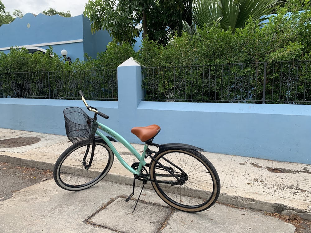 black city bike parked beside blue concrete wall