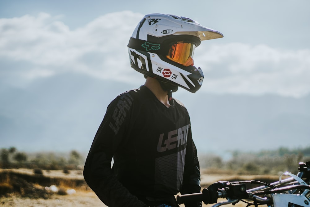 man in black and white long sleeve shirt wearing black helmet riding bicycle during daytime