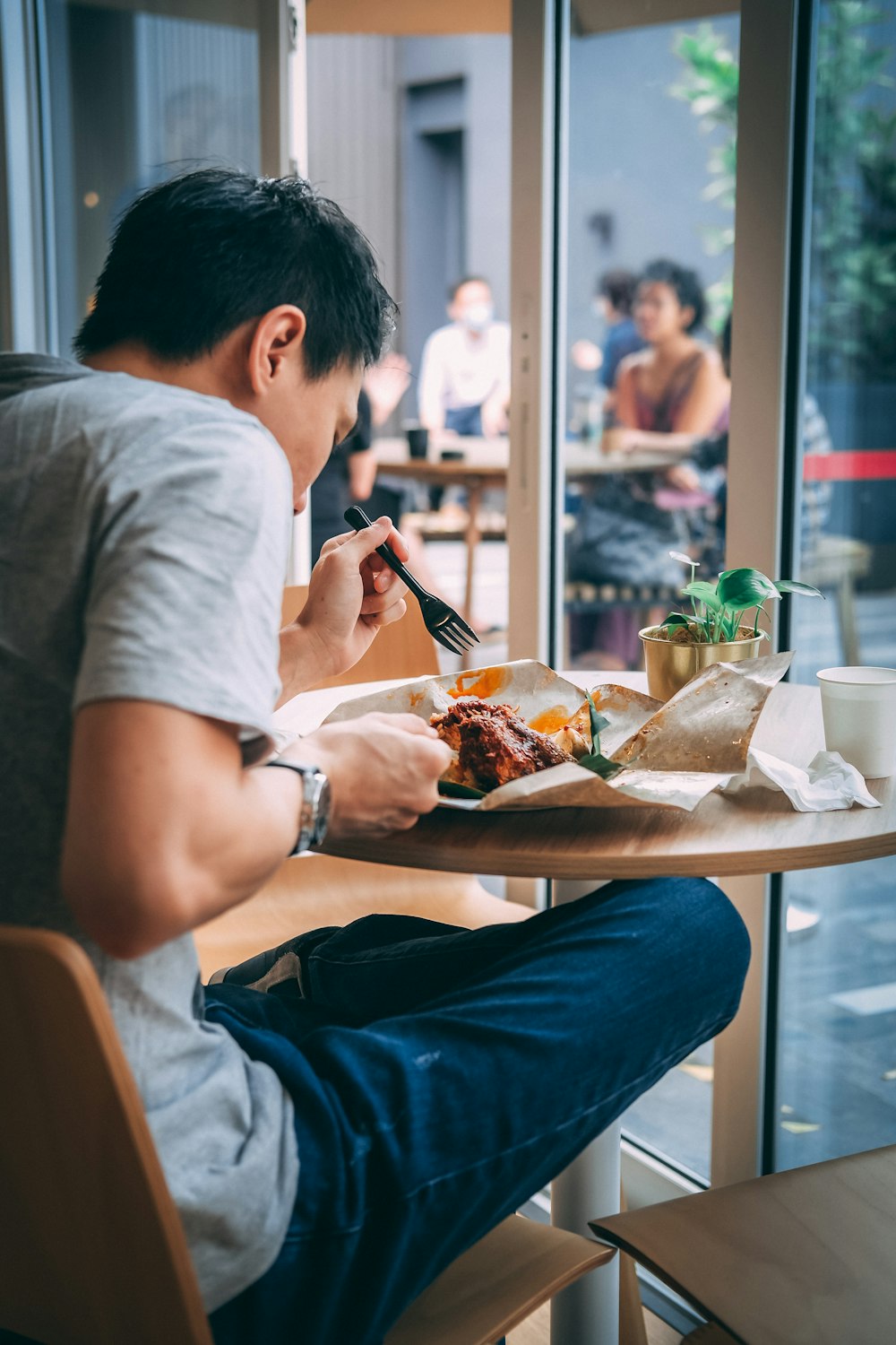 회색 티셔츠를 입은 남자가 식사하는 동안 의자에 앉아 있다