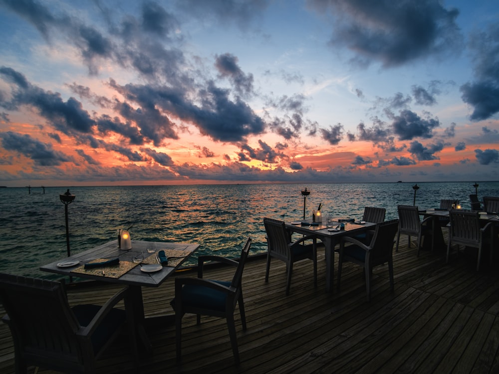 black wooden table and chairs on wooden dock during sunset