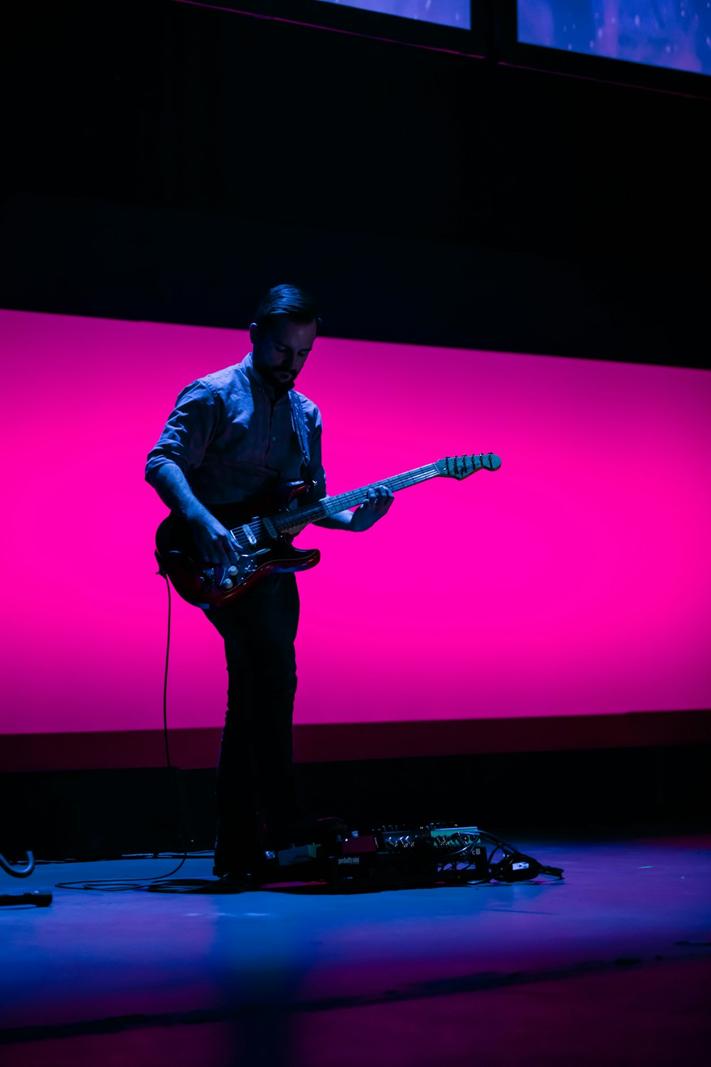 man in blue and white plaid button up shirt playing electric guitar