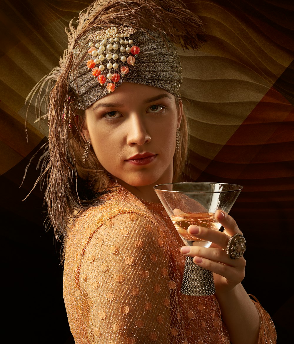 woman in beige knit sweater holding drinking glass