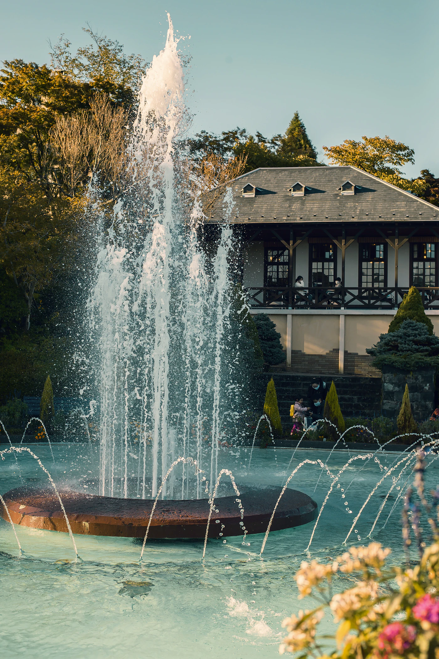 A fountain rising before a grand old house