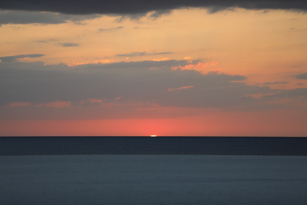 body of water under cloudy sky during sunset