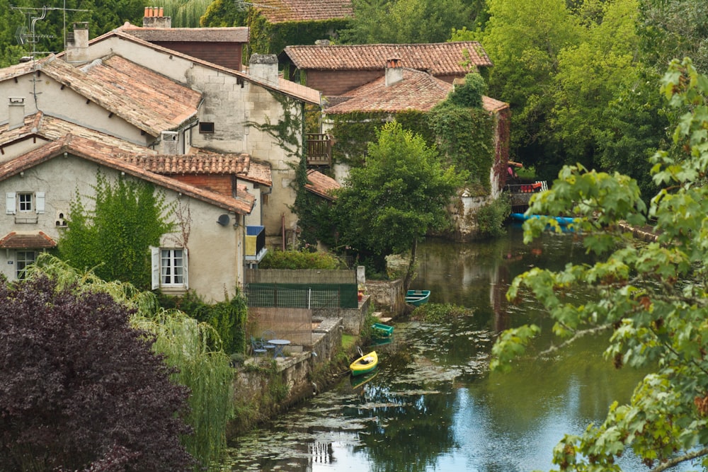 Maison en béton brun et blanc près des arbres verts et de la rivière pendant la journée