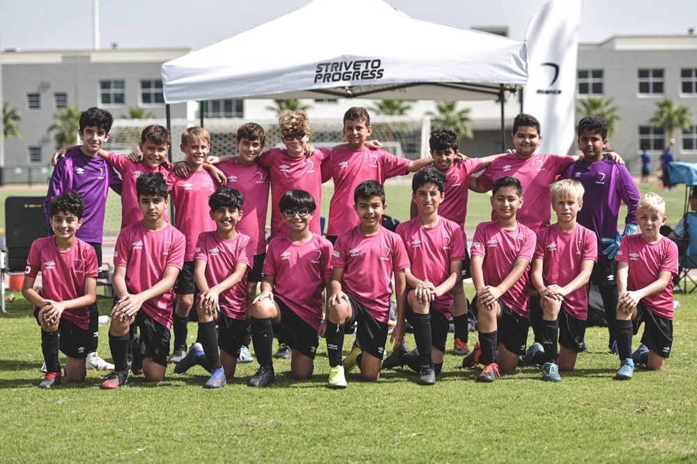 group of people in pink and black shirts on green grass field