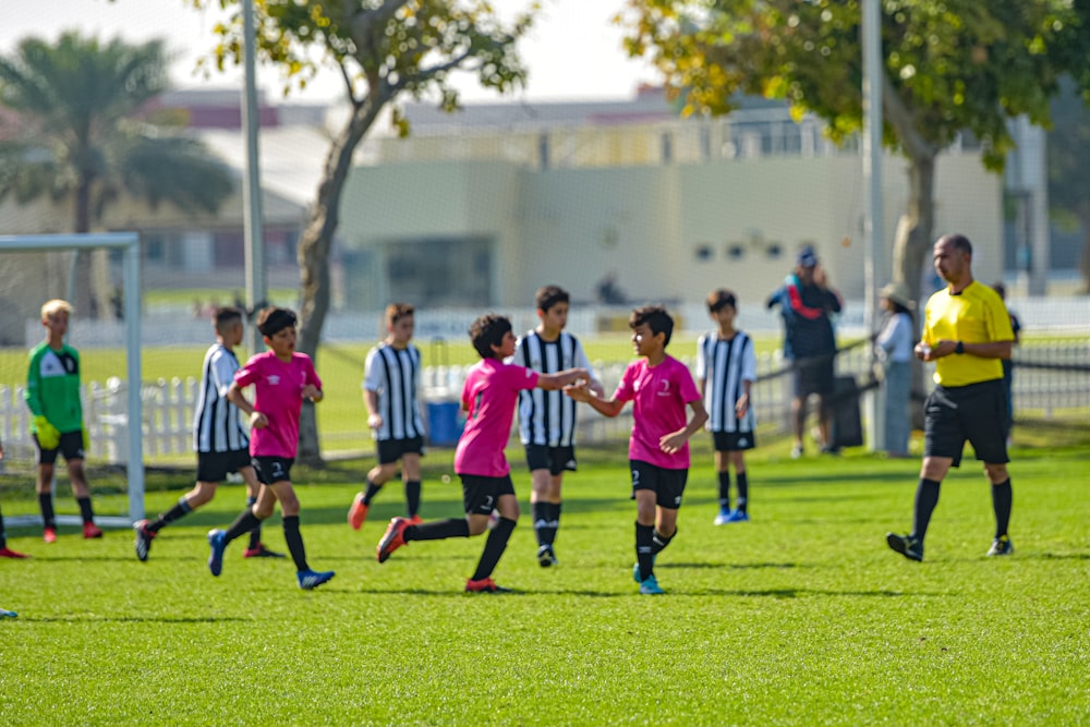 Kinder in rot-weißer Fußballuniform spielen tagsüber auf grünem Rasen