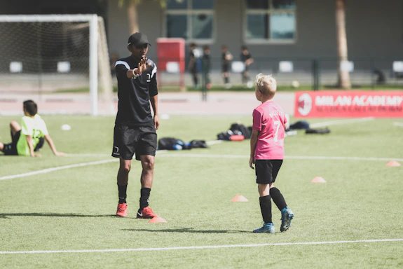 Coach guiding young players during a spirited practice session on a sunny soccer field.