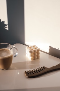 A serene morning scene with a coffee cup and altar & anchor bracelet beside a window with soft sunlight.