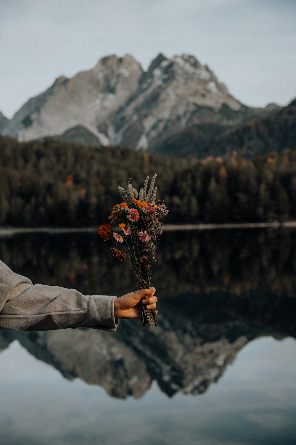 person holding orange and yellow flowers