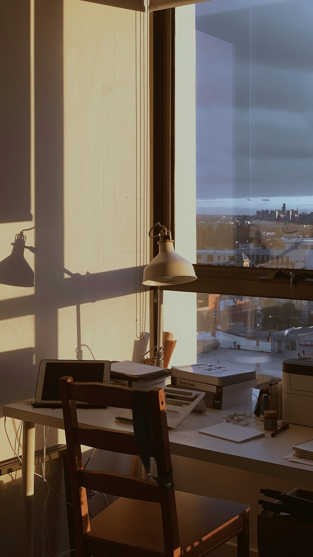 a desk with a chair and a lamp in front of a window