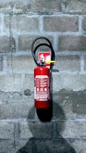 red fire extinguisher on gray concrete wall