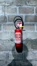 red fire extinguisher on gray concrete wall