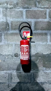 red fire extinguisher on gray concrete wall