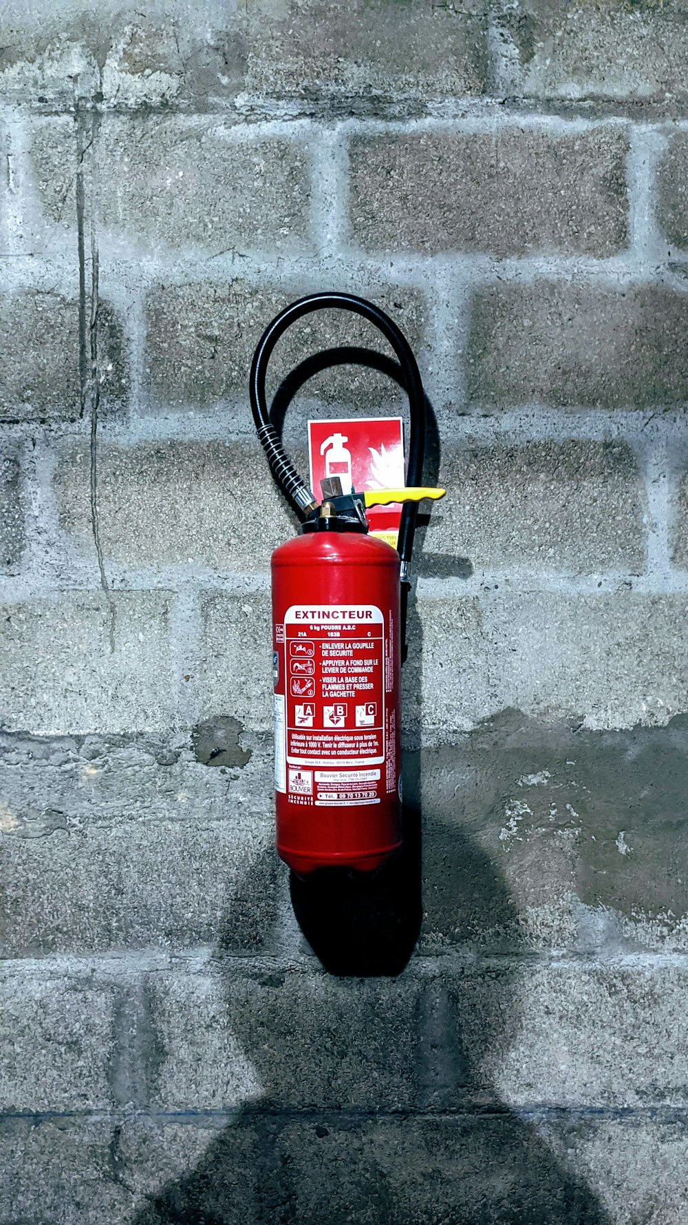 Extintor rojo en pared de concreto gris