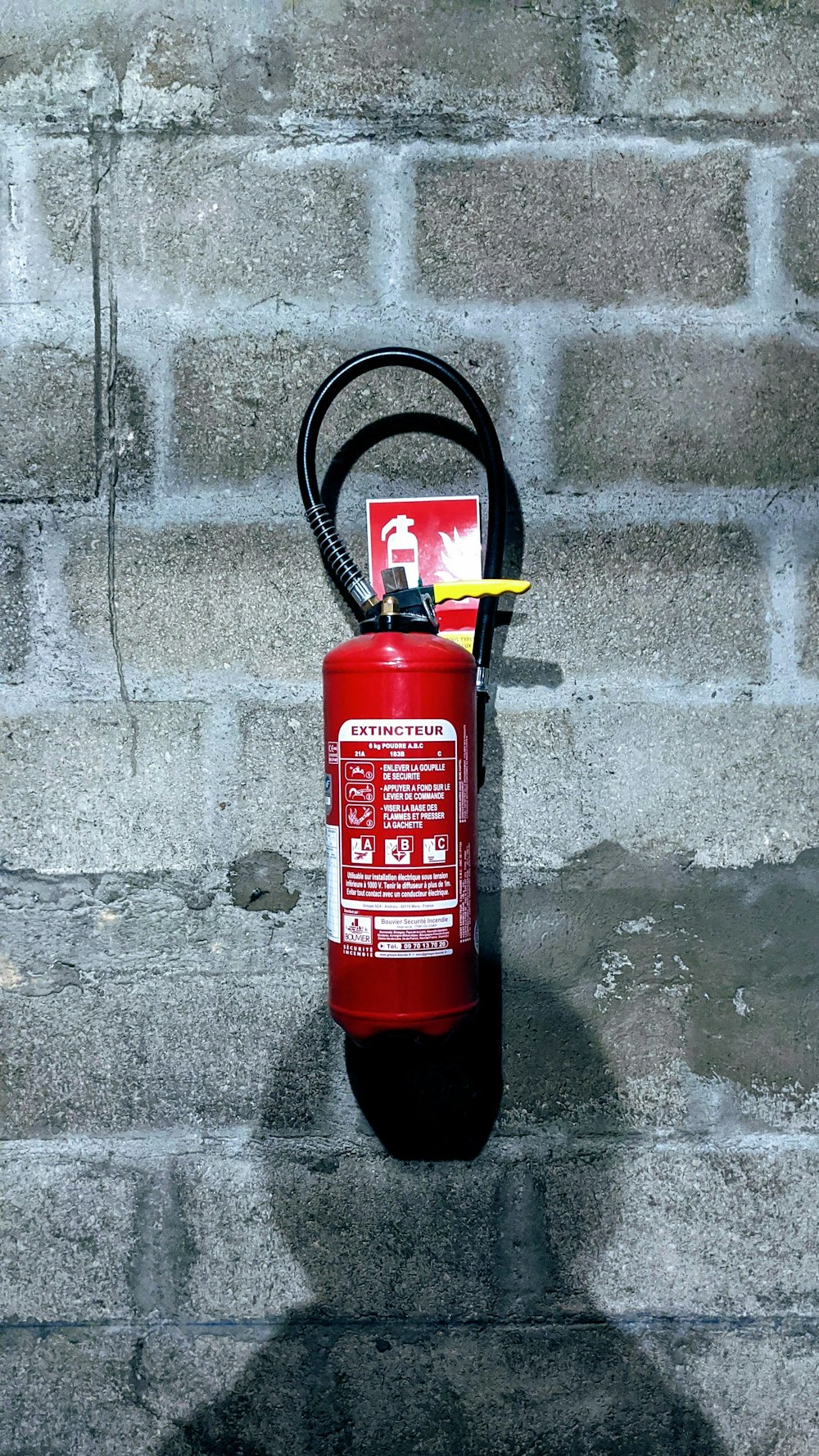 Roter Feuerlöscher an grauer Betonwand