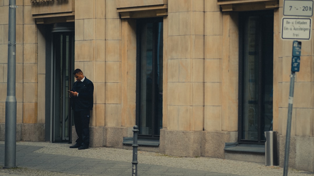 man in black coat standing near black metal post