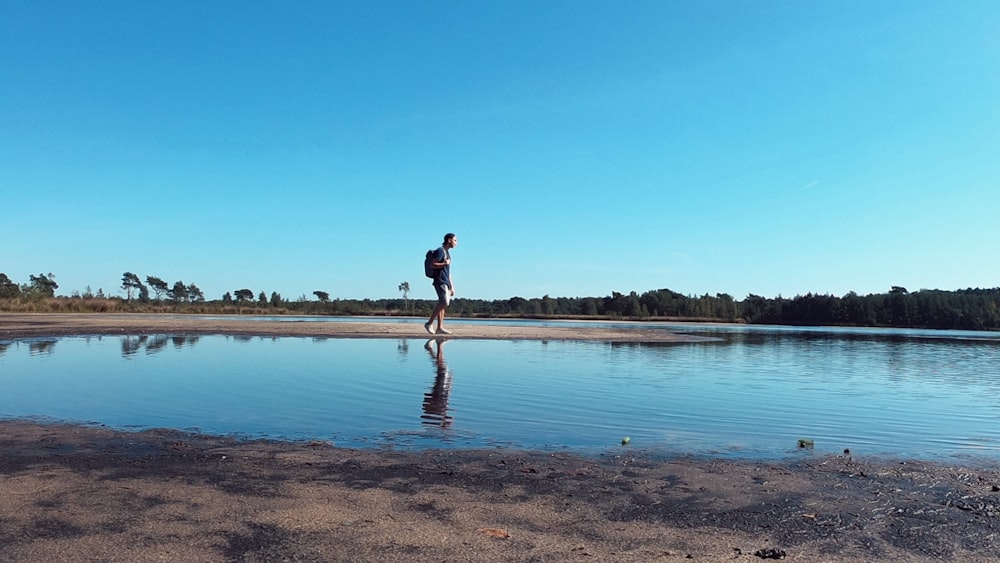 femme en robe noire debout sur le bord de mer pendant la journée