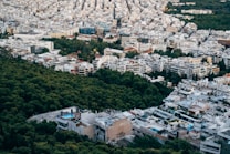 An urban landscape with a dense cluster of buildings interspersed with trees, capturing a blend of city architecture and green spaces. Some buildings have swimming pools on the rooftops, and the layout suggests a mix of residential and possibly commercial use.