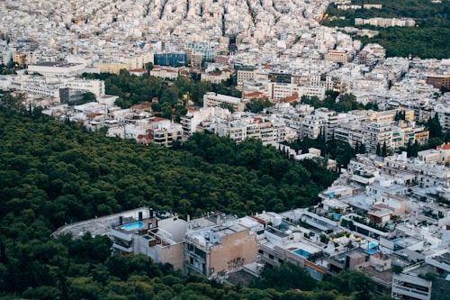 An urban landscape with a dense cluster of buildings interspersed with trees, capturing a blend of city architecture and green spaces. Some buildings have swimming pools on the rooftops, and the layout suggests a mix of residential and possibly commercial use.