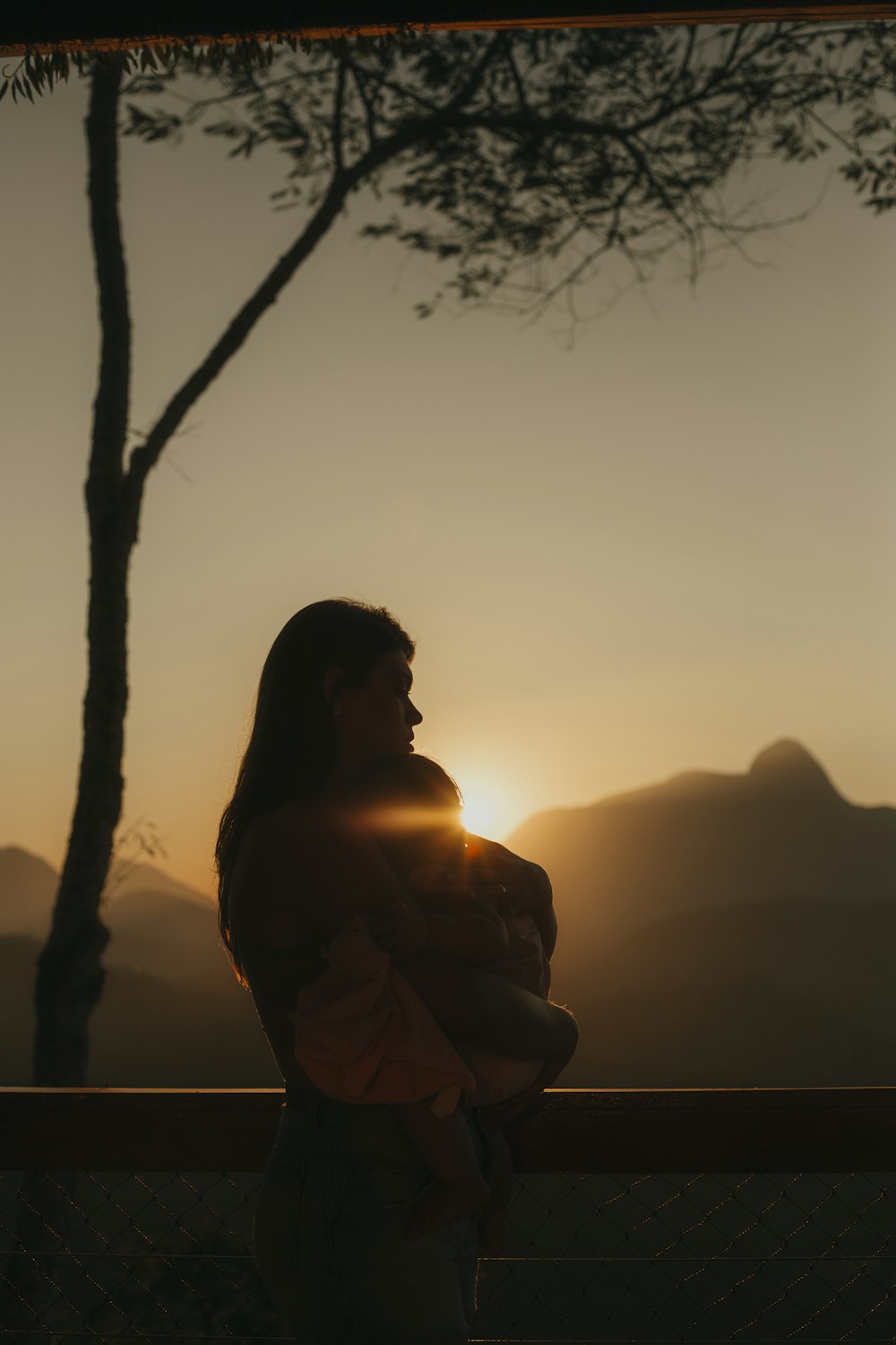 silhouette of man sitting on concrete wall during sunset