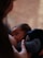 A close-up of a baby breastfeeding, with a soft, intimate focus. The baby's gaze is upward, and the person's hand gently holds the baby, conveying a sense of care and tenderness.