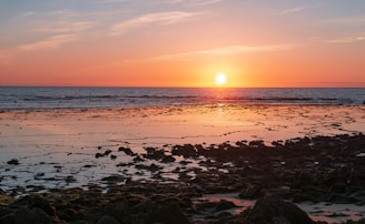 sea waves crashing on shore during sunset