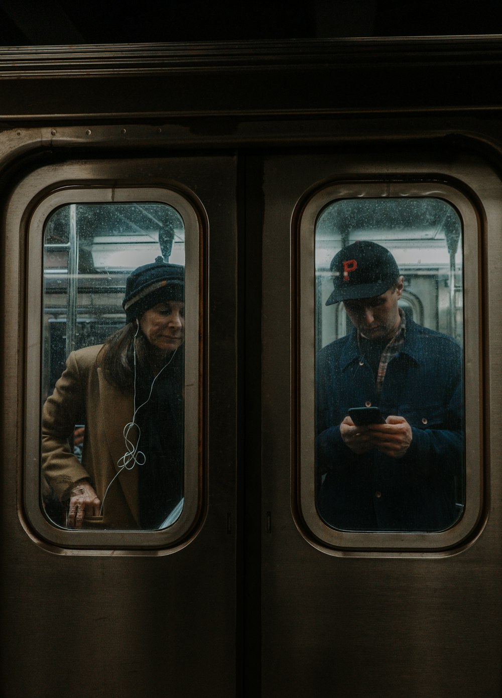 man in brown jacket standing in train
