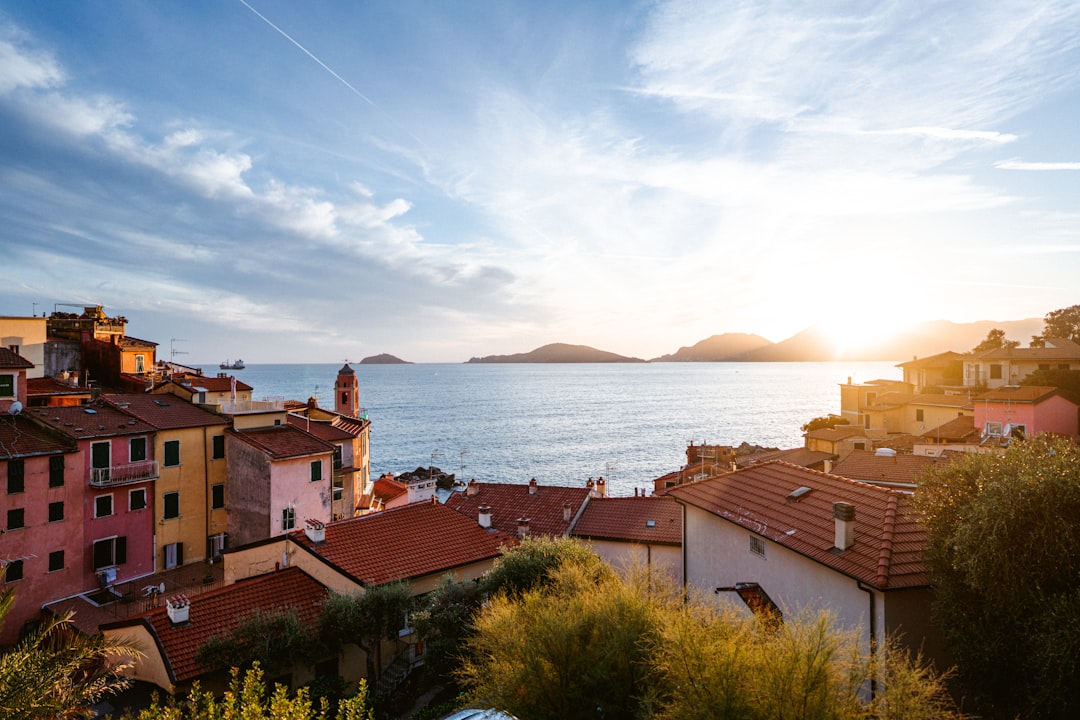 brown and white concrete houses near sea under white clouds during daytime