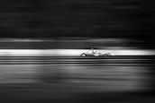 Dynamic shot of a race car speeding on a track, blurring the background in silver and grey tones.