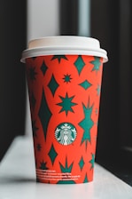 Close-up of a sleek travel tumbler with a vibrant orange star logo against a deep blue galaxy background.