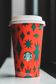 Close-up of a sleek travel tumbler with a vibrant orange star logo against a deep blue galaxy background.
