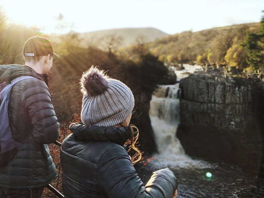 man and woman sitting on rock during daytime