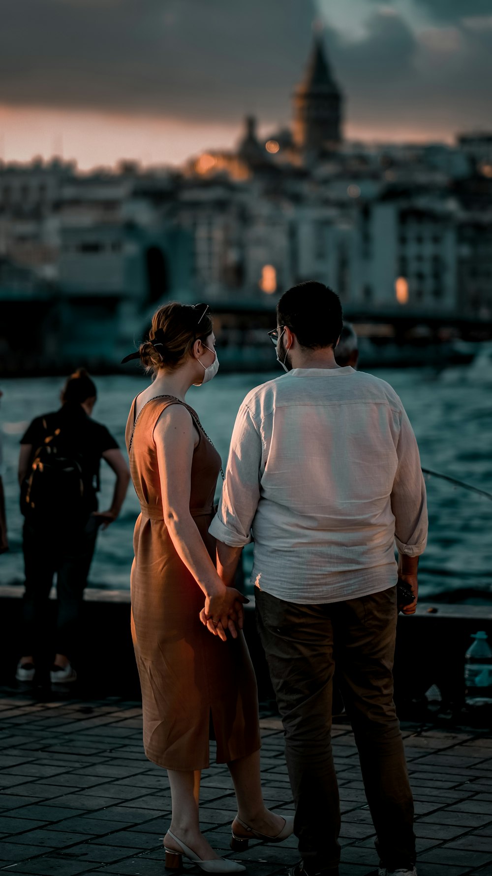 man in white tank top and black pants standing beside woman in black jacket during daytime