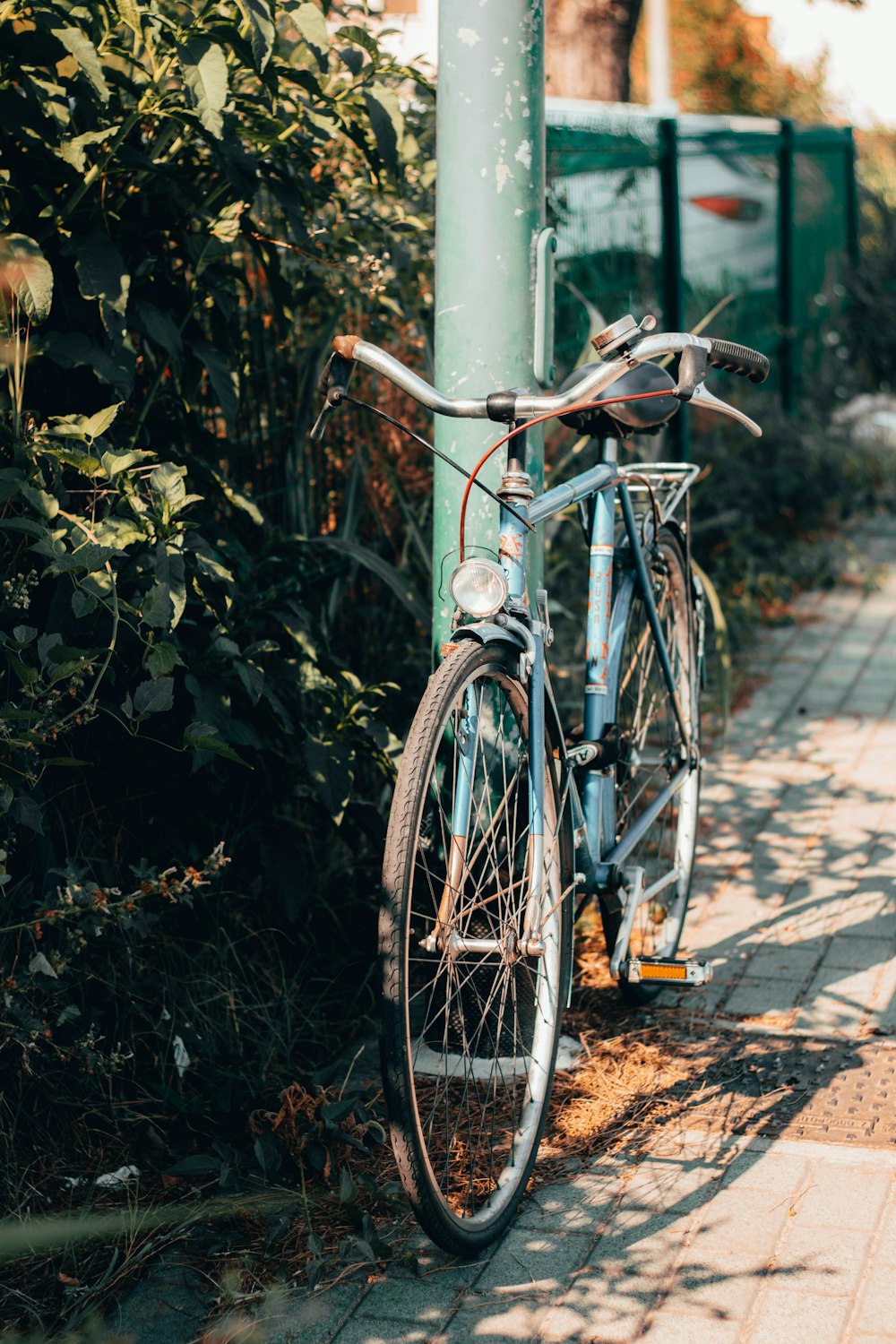 blue city bike parked beside green metal post