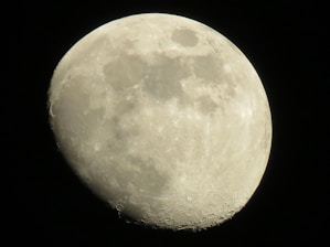 A close-up view of the moon showcasing its craters and surface details against a dark black sky. The moon appears illuminated, with a clear representation of its texture and shadows.