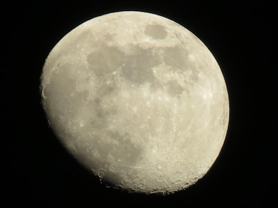 A close-up view of the moon showcasing its craters and surface details against a dark black sky. The moon appears illuminated, with a clear representation of its texture and shadows.
