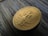 Close-up of a shiny gold coin resting on a velvet cloth.